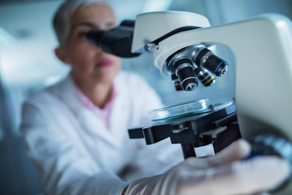 une chercheuse regarde a travers un microscope