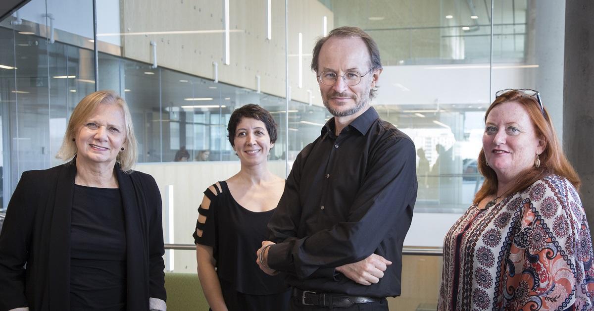 Trois femmes et un homme, debout côte à côte.