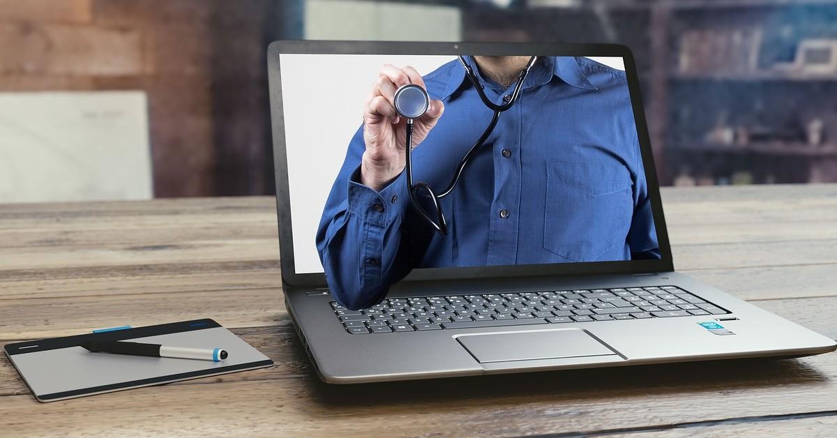 Personne tenant un stéthoscope sur un écran d'ordinateur