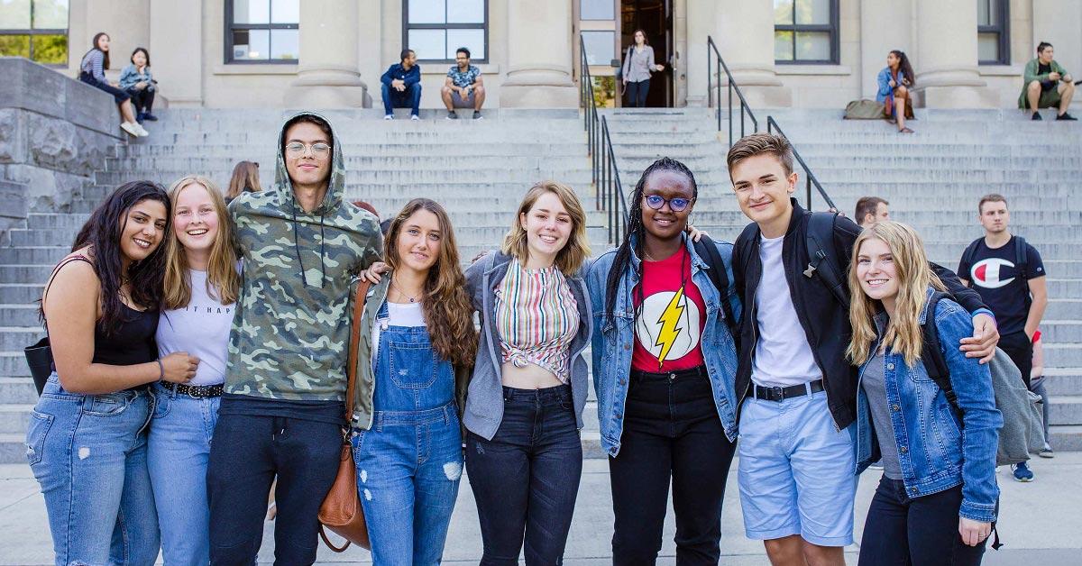 A diverse group of uOttawa students linking arms outside Tabaret Hall.