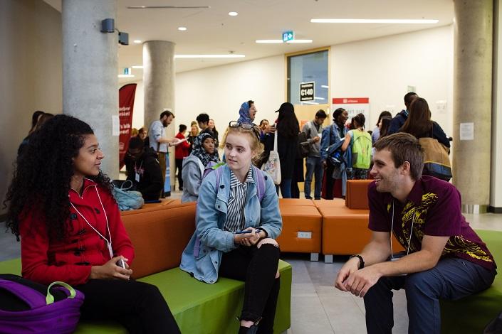 Deux étudiantes et un étudiant discutent ensemble pendant la pause. 