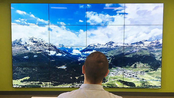 Un étudiant contemple le relief montagneux que lui renvoient 16 écrans juxtaposés.