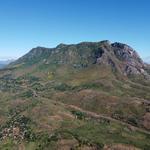 A mountain in the background with a small forest in the foreground